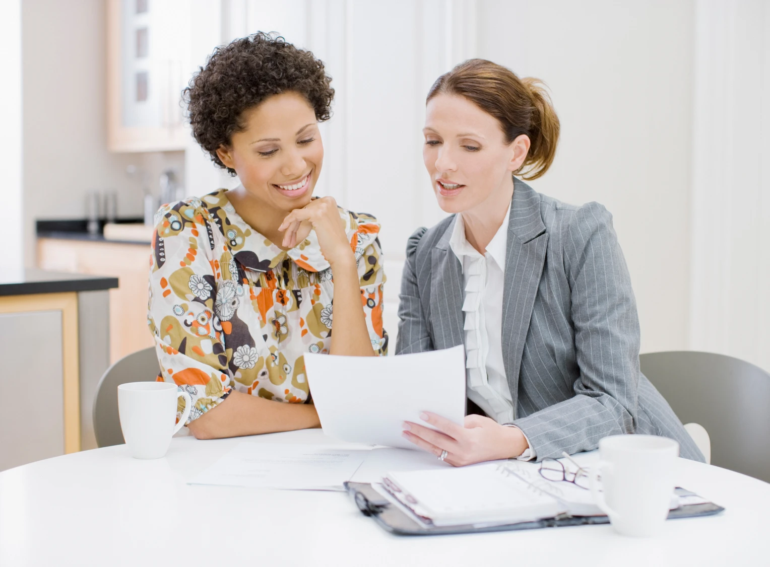 Two women discussing documents at table.