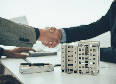 Handshake over model building on desk.