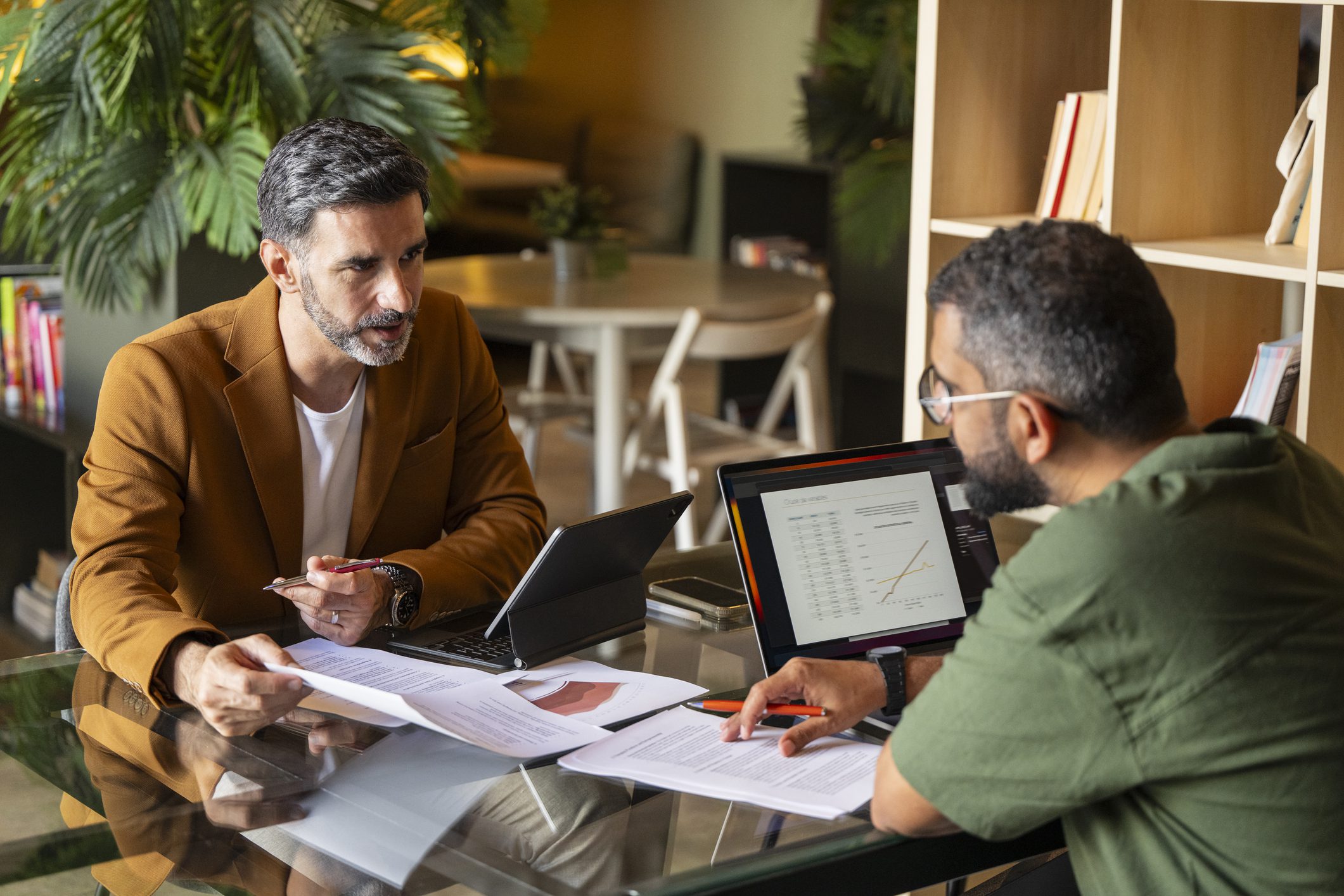 Two men discussing work at table.