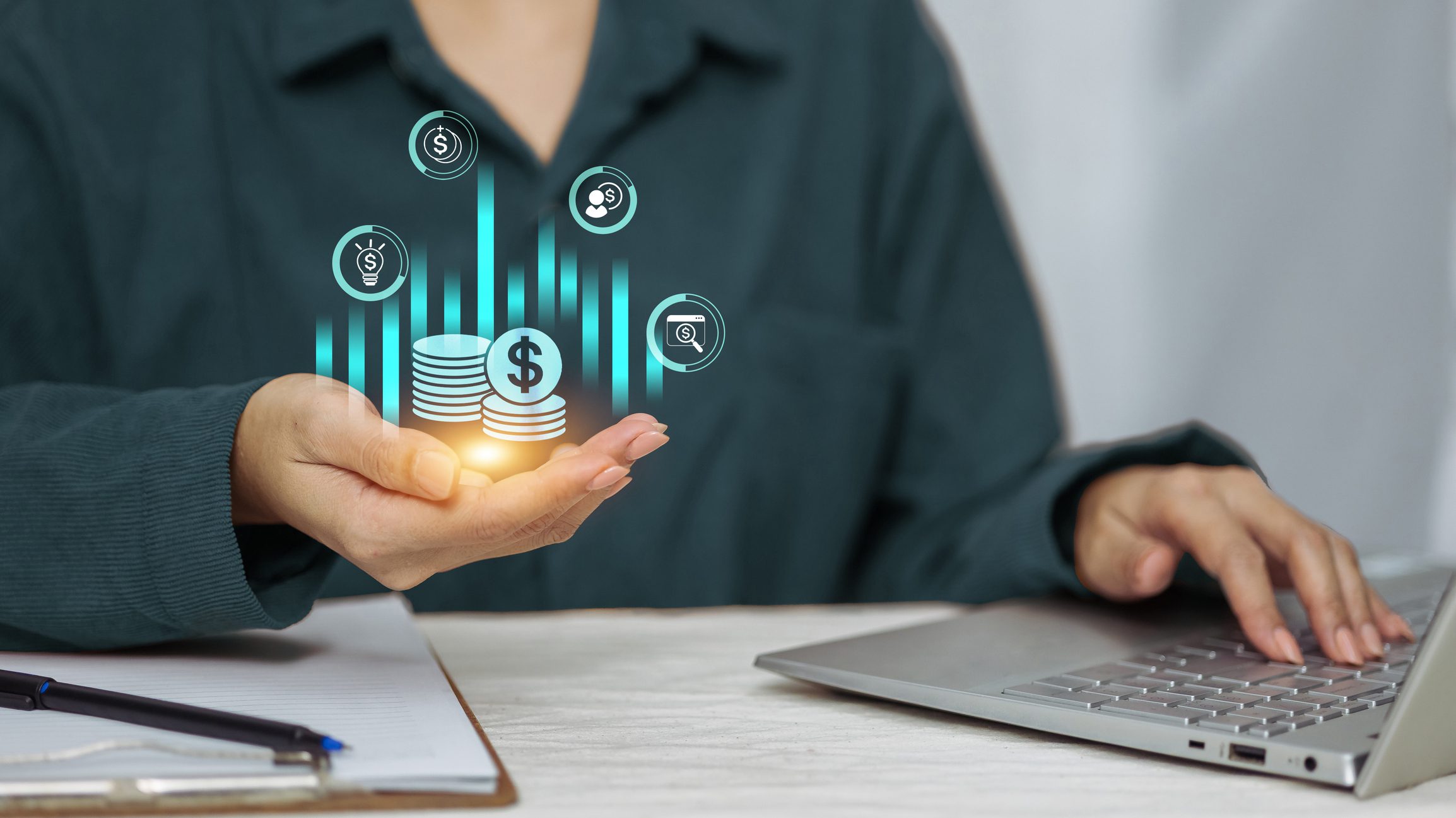 Person using laptop with virtual financial graphics.