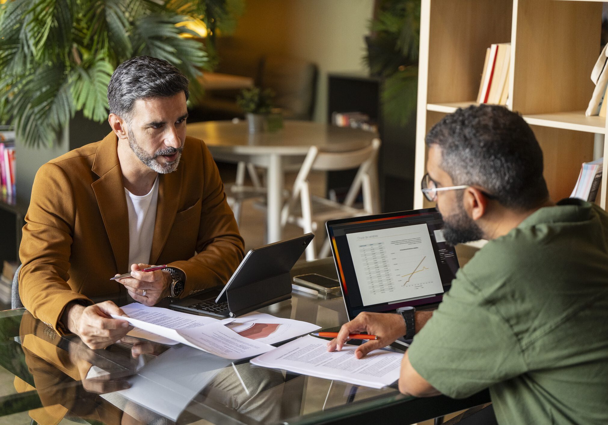 Two men discussing work at table.