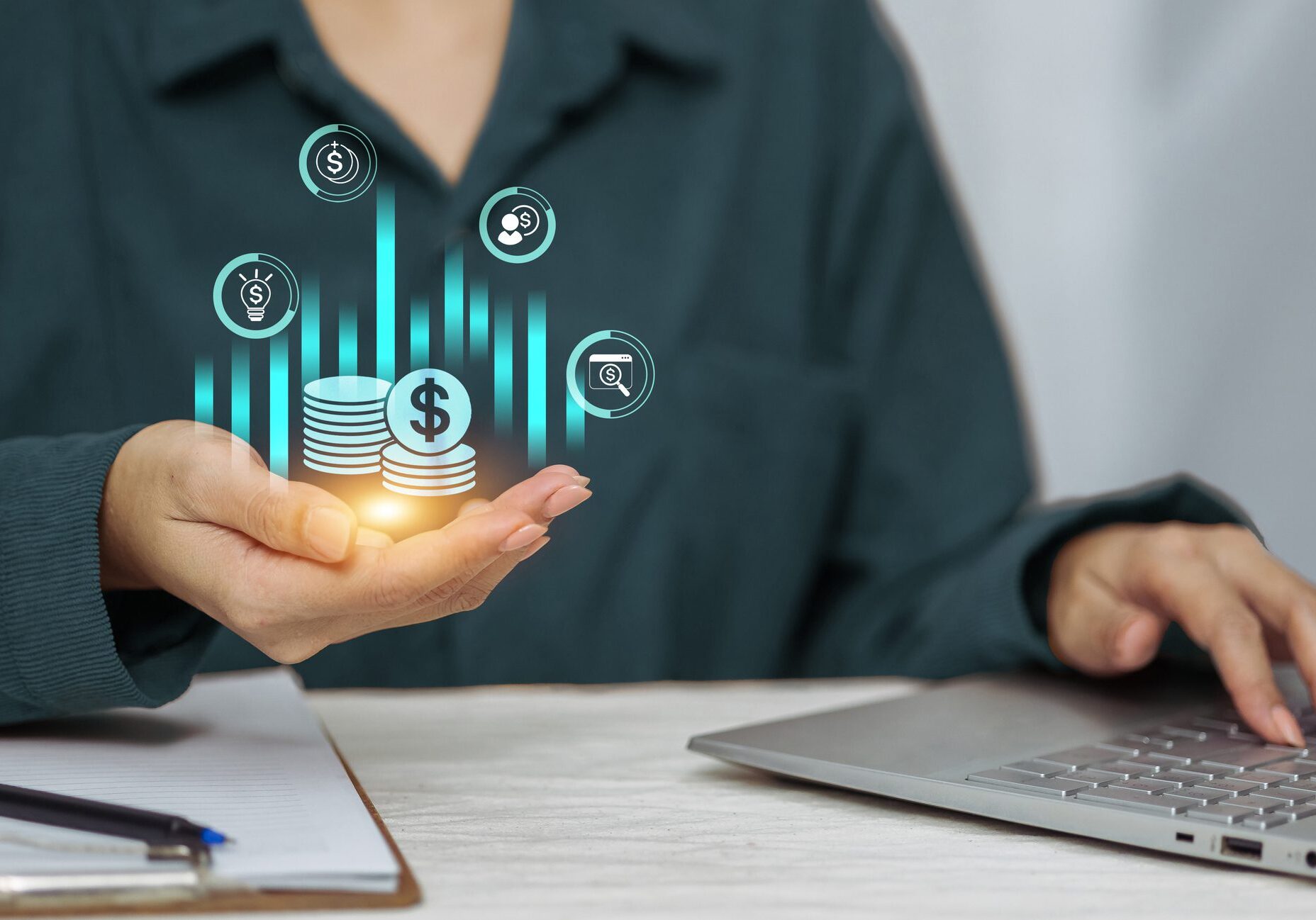Person using laptop with virtual financial graphics.